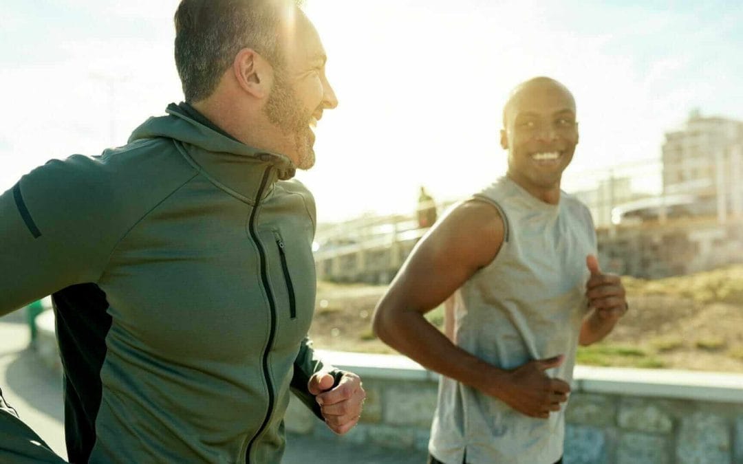 Two smiling male friends running together to stay fit in the New Year.